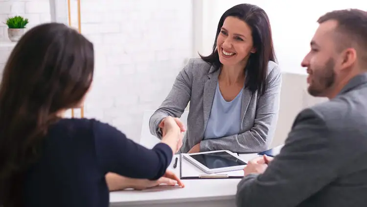 A businesswoman shakes hands with a supplier across a meeting table